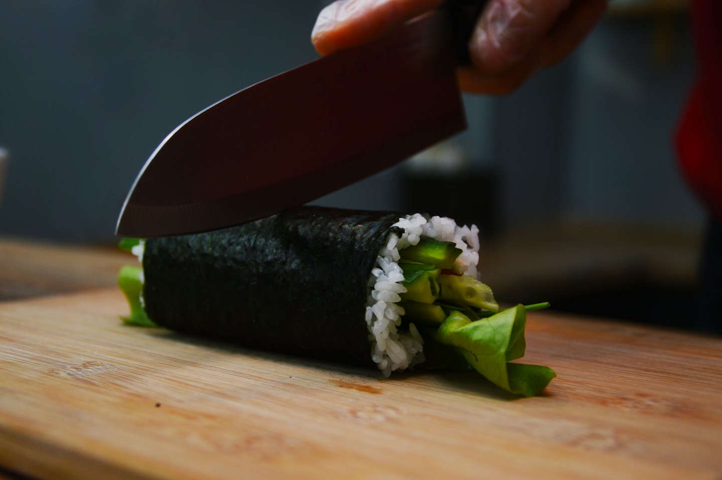 Szef kuchni kroi nożem świeżą rolkę sushi.