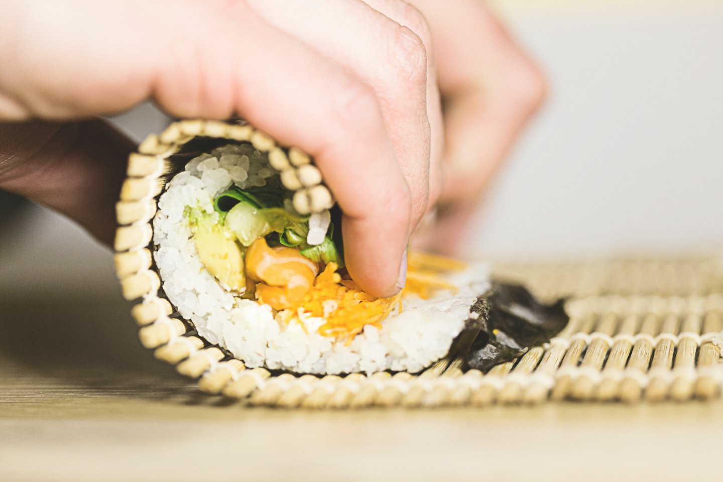 Ręczne zwijanie świeżego sushi maki z łososiem i awokado.
