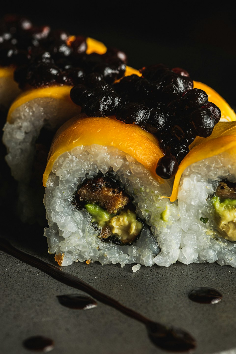 Roladki sushi z plasterkami mango na talerzu.